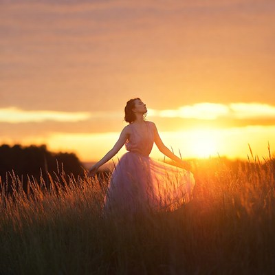 Woman in pink dress in sunset field