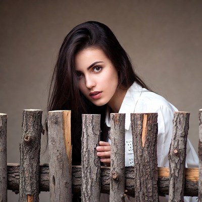 Woman peeking over wooden fence