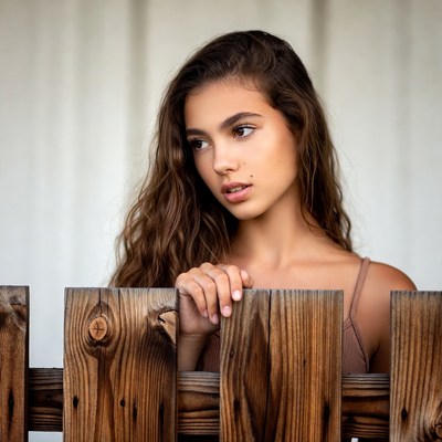 Young woman leaning on wooden fence