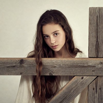 Girl peeking over wooden fence