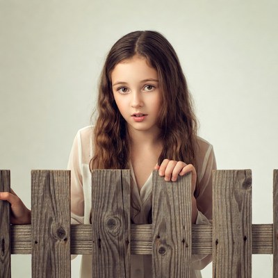 Girl peeking over wooden fence
