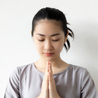 Asian woman praying with hands clasped