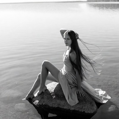 Woman sitting on rock by lake