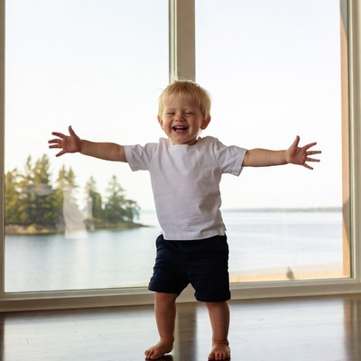 Blond toddler arms outstretched by lake window