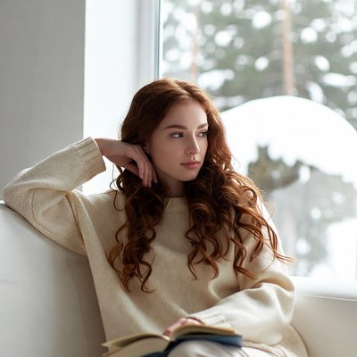 Redhead woman reading by snowy window