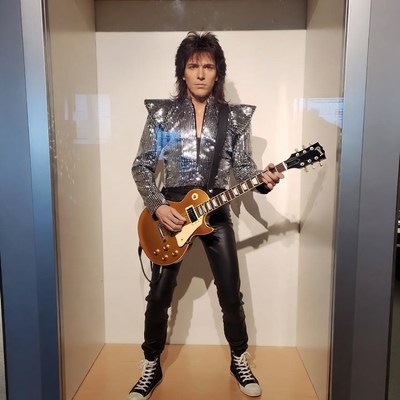 Man in silver outfit holding Les Paul guitar