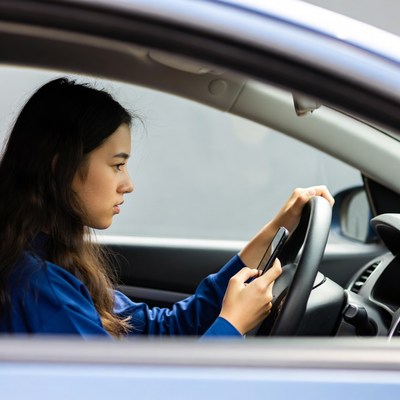Asian woman driving while using phone