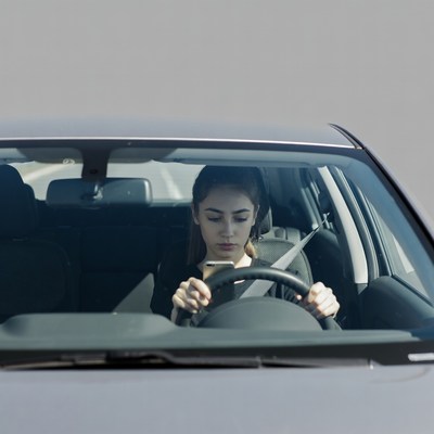 Woman driving car texting phone