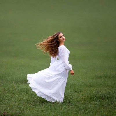 Woman in white dress in green field