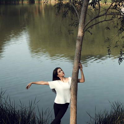 Woman leaning on tree by lake