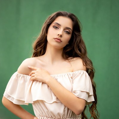 Woman in off-shoulder dress on green background