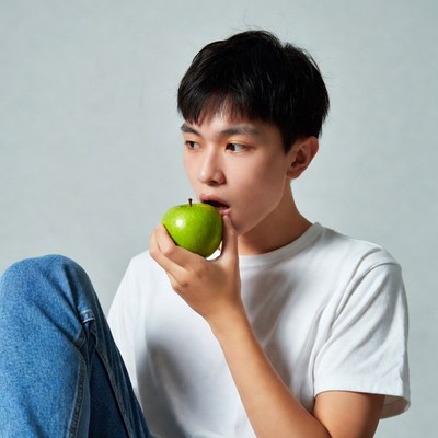 Young Asian man biting green apple