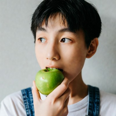 Asian boy eating green apple