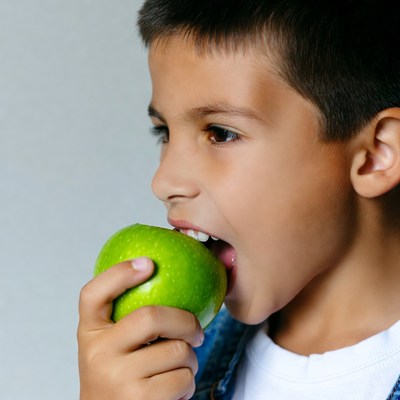 Boy biting green apple