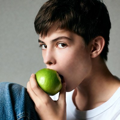 Boy biting green apple