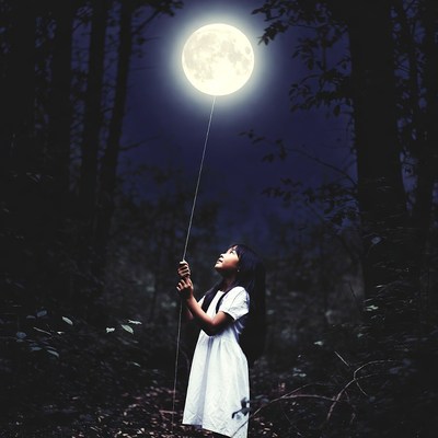 Girl holding moon balloon in forest