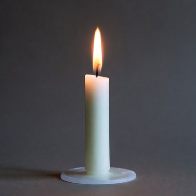 Burning white candle on holder
