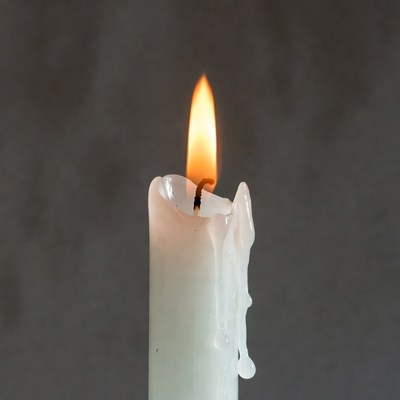 Burning white candle with dripping wax