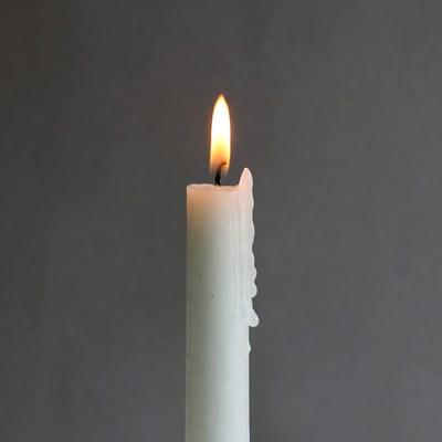 Burning white candle with dripping wax