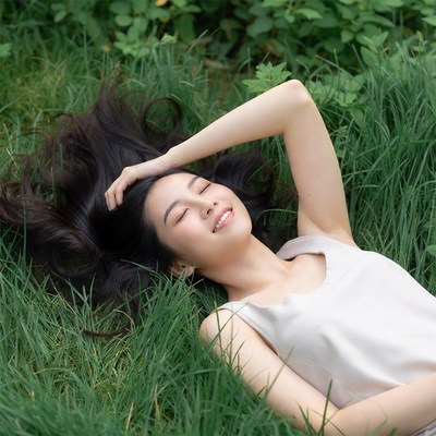 Asian woman lying in green grass