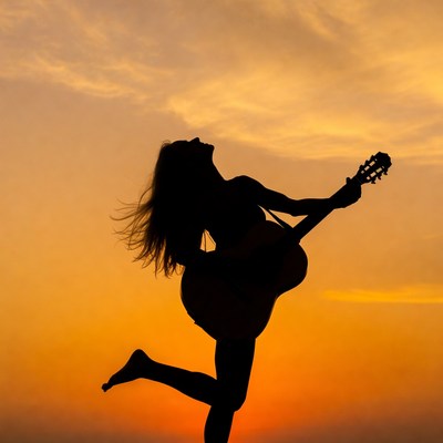 Woman playing guitar silhouette sunset
