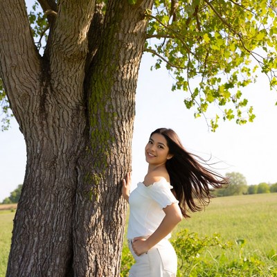 Asian girl smiling by tree in field