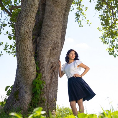 Asian woman leaning against tree