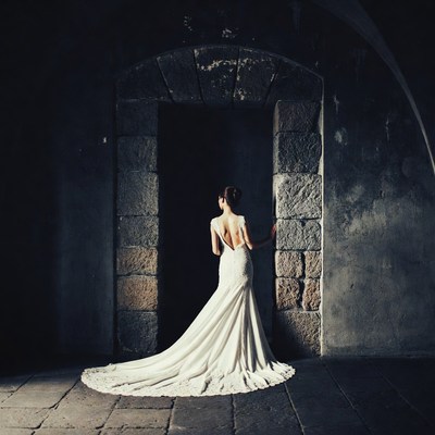 Woman in white gown at stone archway