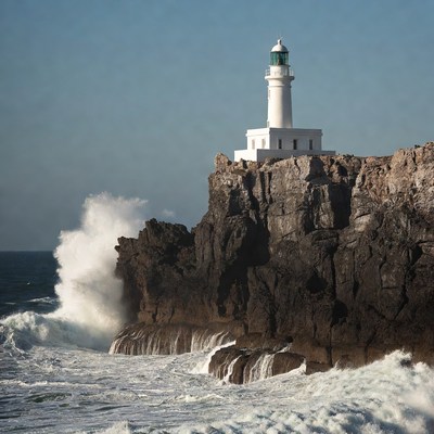 White Lighthouse on Rocky Cliff with Crashing Waves