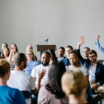 Diverse group raising hands in meeting