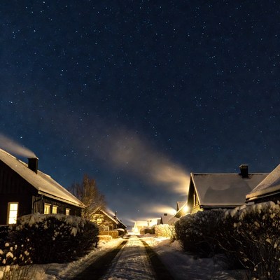 Snowy village street under starry night sky