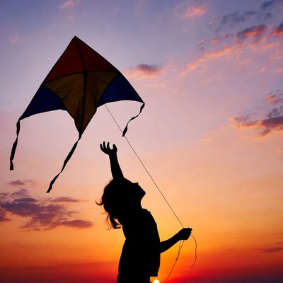 Girl flying kite silhouette sunset