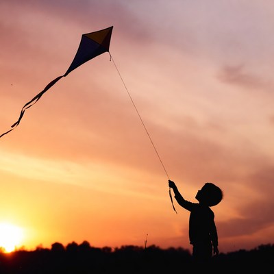 Boy flying kite at sunset
