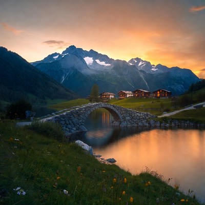 Stone Bridge over Lake with Swiss Chalet Mountains