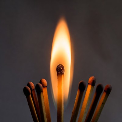 Burning matchstick surrounded by matches