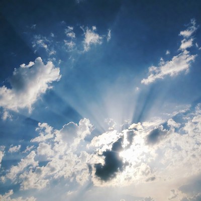 Sun rays through clouds in blue sky