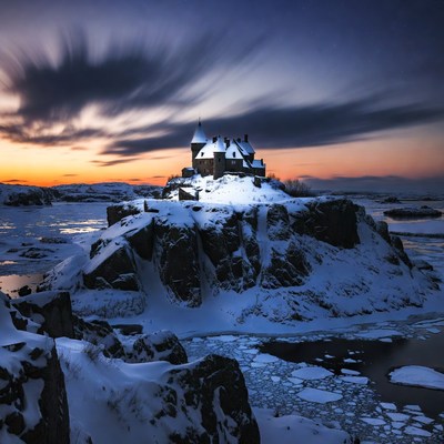 Snowy Castle on Rocky Island at Sunset