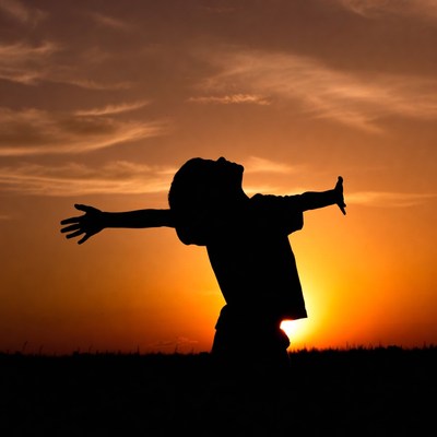 Boy silhouette arms outstretched sunset