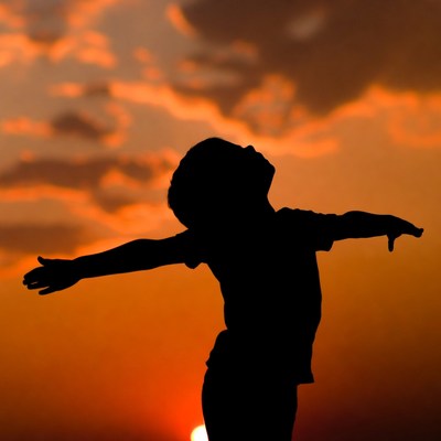 Boy silhouette arms outstretched sunset
