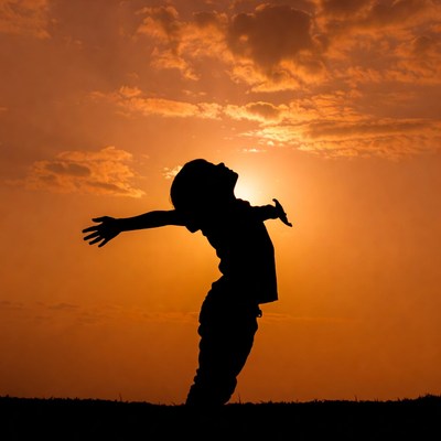 Boy silhouette arms outstretched sunset