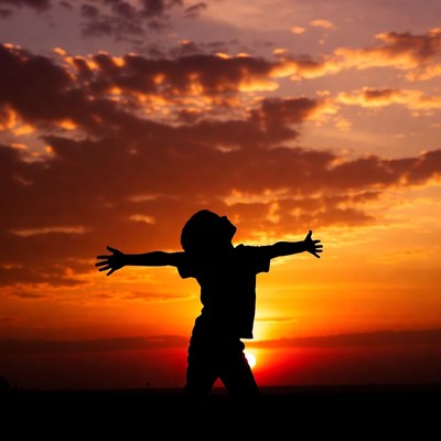 Boy silhouette arms outstretched sunset