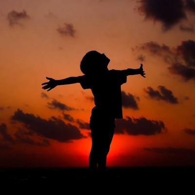 Boy silhouette spreading arms at sunset