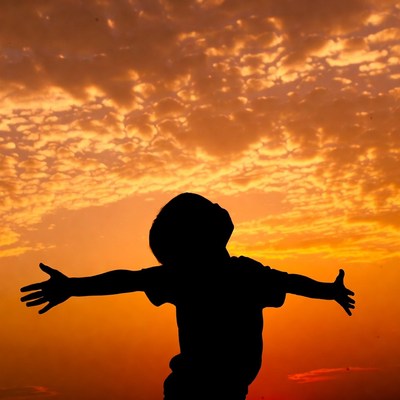Boy silhouette arms outstretched sunset