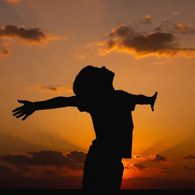 Boy silhouette arms outstretched sunset