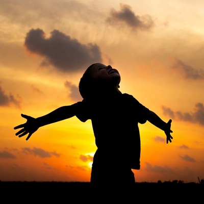Boy silhouette arms outstretched sunset
