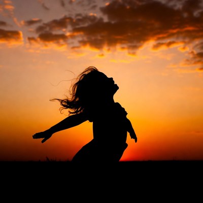 Girl silhouette spreading arms at sunset