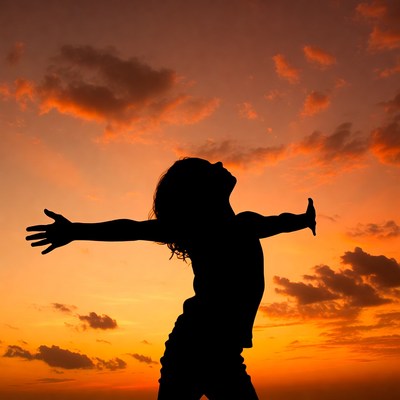 Girl spreading arms in sunset silhouette