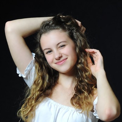 Smiling girl with curly hair raising arms