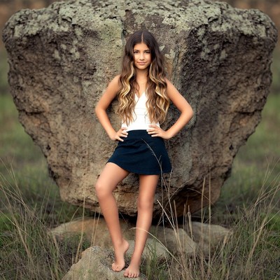 Girl posing barefoot by large rock