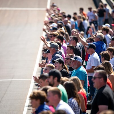 Crowd cheering along racetrack fence